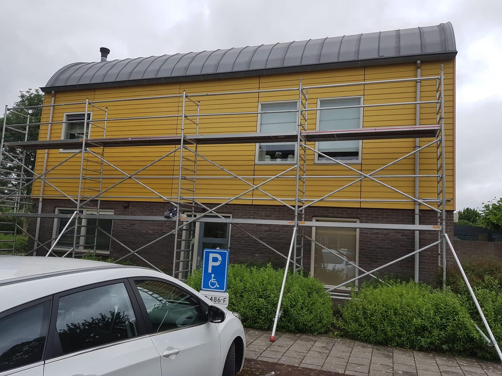 Woning met gele houten gevelbekleding in de steigers